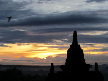 Silhouette of statue against cloudy sky