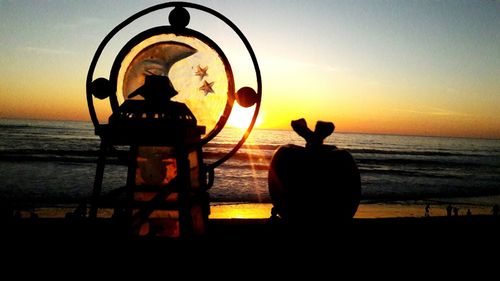 Silhouette people standing by sea against sky during sunset