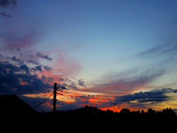 Silhouette houses against dramatic sky during sunset