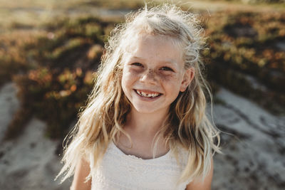 Portrait of young school age girl with freckles smiling at camera