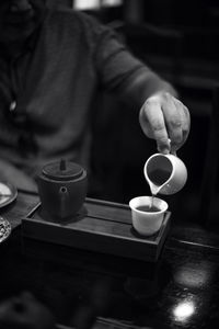 Midsection of man holding coffee on table