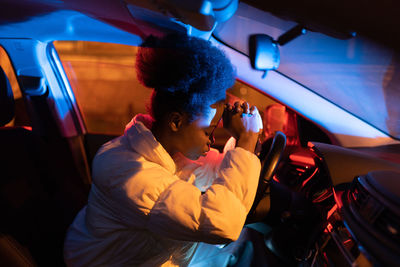 Tired african woman driver sleeping napping with head on steering wheel, depressed black girl in car