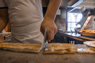 Chef cutting turkish pide into slices on table at restaurant