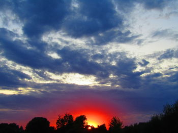 Low angle view of silhouette trees against dramatic sky