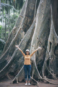 Cheerful woman standing by tree trunk