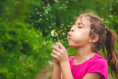 Girl blowing dandelion flower in garden