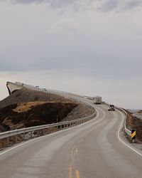 Empty country road against cloudy sky