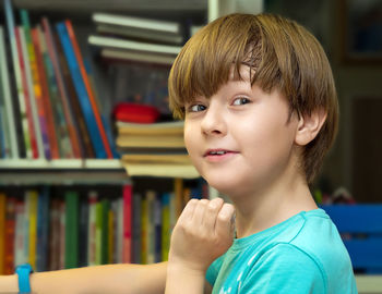 Schoolboy is smile and looking camera near a bookshelves