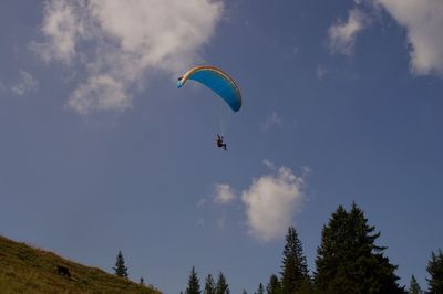 Low angle view of person paragliding against sky