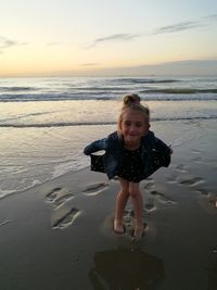 Full length of smiling girl on beach against sky