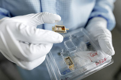 Hands of male scientist unpacking laser chips