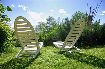 Empty chairs on field against sky