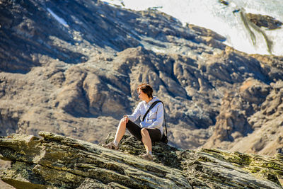 Young woman sitting on rock formation