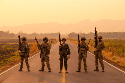 Armed forces standing against sky during sunset