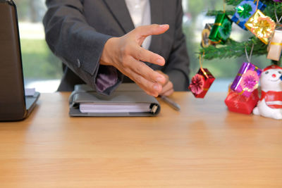 Midsection of businessman offering hands on table during christmas