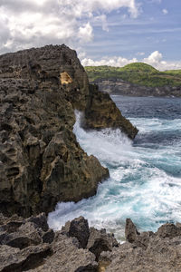 Scenic view of rocks on sea shore against sky