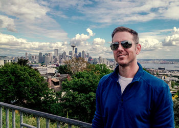 Portrait of man in sunglasses standing against cityscape