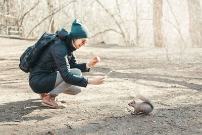 Woman taking picture photo of squirrel in park. tourist girl snapping photos of wild animal