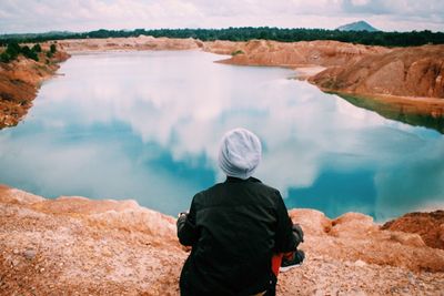 Rear view of man looking at lake against mountain