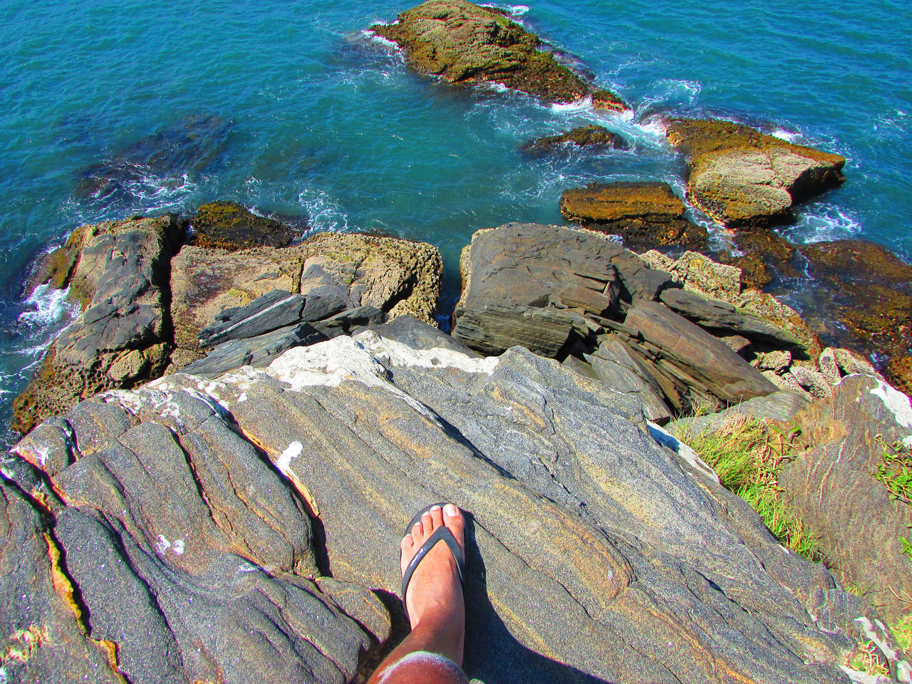 water, rock, human leg, low section, sea, coast, one person, shore, cliff, personal perspective, leisure activity, high angle view, lifestyles, terrain, nature, ocean, day, beach, shoe, land, beauty in nature, scenics - nature, human foot, outdoors, standing, relaxation, adult, sunlight, rock formation, women, geology, limb, tranquility, trip, holiday, vacation, idyllic, tranquil scene