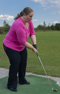 Side view of young woman standing on golf course