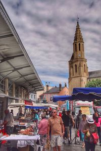 People in front of building against cloudy sky