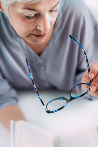 Senior woman with eyeglasses having problems with book reading