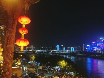 Illuminated lanterns hanging by buildings in city at night