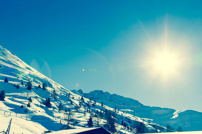 Low angle view of snowcapped mountains against blue sky