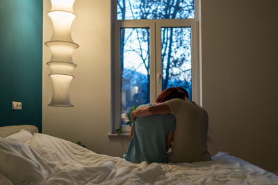 Rear view of woman looking through window