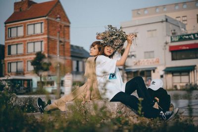 Woman with arms outstretched standing against built structure