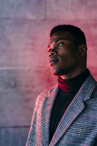 Portrait of young man looking away against wall