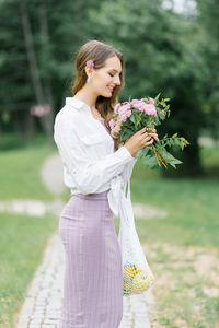 A pretty young woman holds a bouquet of pink garden spirea flowers in her hands. walking in nature 