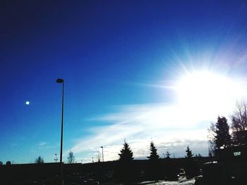 Low angle view of illuminated street light against blue sky