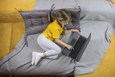 High angle view of girl using laptop on sofa