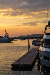 Boats moored at harbor against sky during sunset