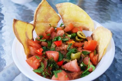 Nacho chip with salad served in bowl on table