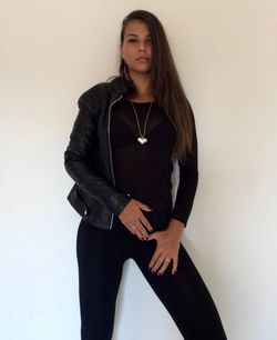 Portrait of young woman standing against white wall
