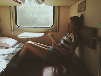 Young woman reading book while resting in train