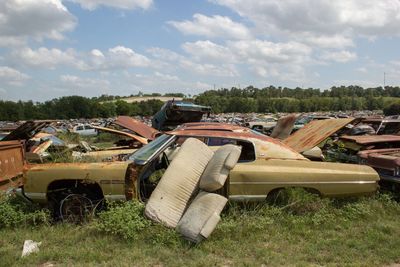 Abandoned vehicle on field against sky