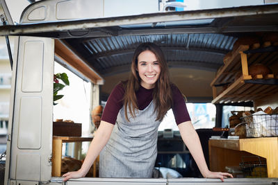 Portrait of smiling young female owner standing in food truck