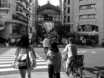 Rear view of people walking on road in city