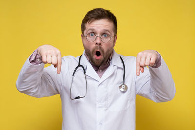 Portrait of man standing against yellow background