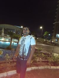 Young man standing on illuminated street at night