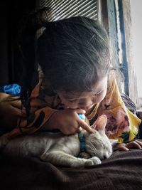 Close-up of girl playing with sleeping kitten at home