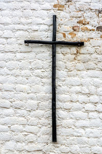 Black wooden cross on old white wall