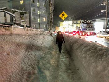 Man walking on illuminated road in city