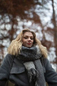 Portrait of smiling young woman standing against trees