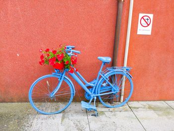 Bicycle parked against red wall