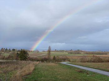 Scenic view of rainbow over field against sky